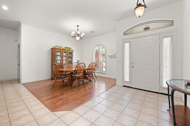 foyer featuring light tile patterned floors, ornamental molding, and an inviting chandelier