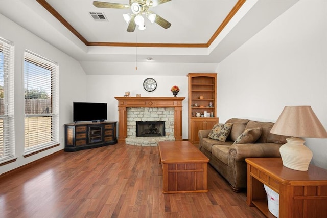 living room with a ceiling fan, visible vents, a tray ceiling, and wood finished floors