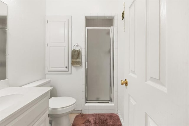 bathroom with toilet, a stall shower, and vanity