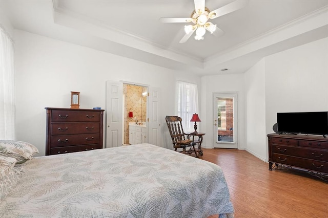 bedroom with baseboards, ornamental molding, wood finished floors, access to outside, and a tray ceiling