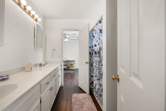 full bath with double vanity, a shower with curtain, a sink, and wood finished floors