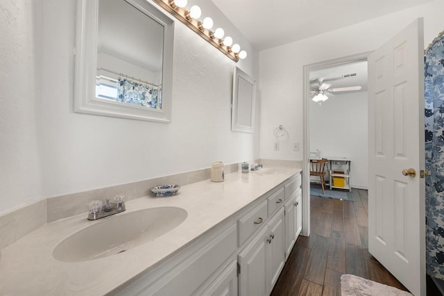 bathroom with double vanity, ceiling fan, a sink, and wood finished floors