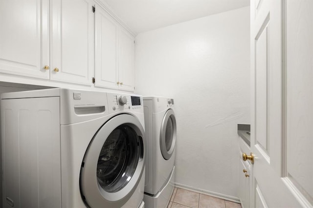 laundry room featuring light tile patterned floors, washer and clothes dryer, cabinet space, and baseboards