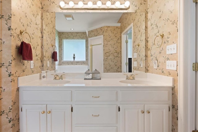 full bath featuring double vanity, a sink, and wallpapered walls