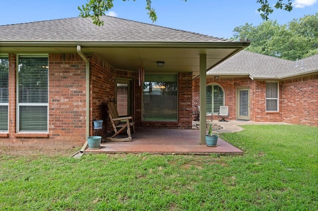 rear view of house featuring brick siding, a patio, and a lawn