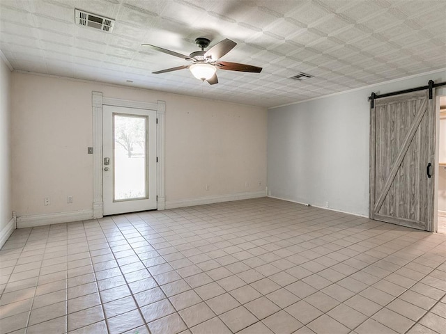 tiled spare room featuring ceiling fan and a barn door