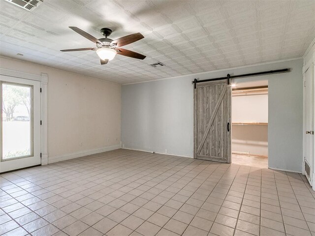 tiled spare room with ceiling fan and a barn door