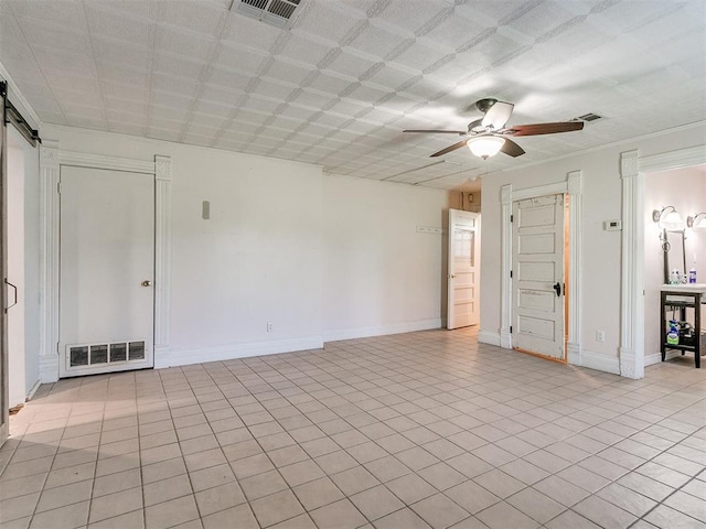 empty room with ceiling fan, light tile patterned flooring, and a barn door