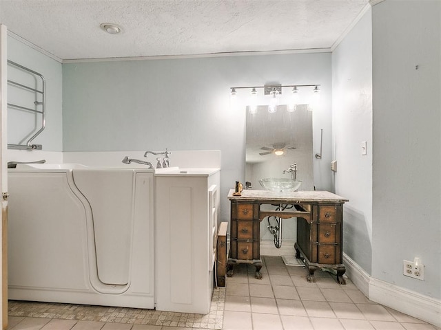 bathroom with ceiling fan, a tub, a textured ceiling, ornamental molding, and sink