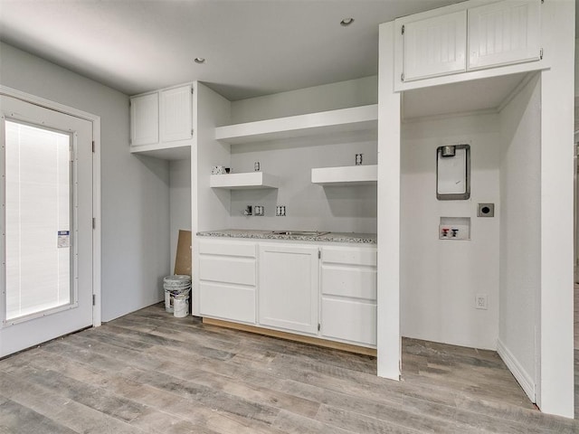 kitchen featuring light wood-type flooring, white cabinetry, and light stone counters