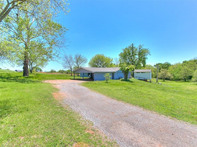 single story home featuring a front lawn, a rural view, and a carport