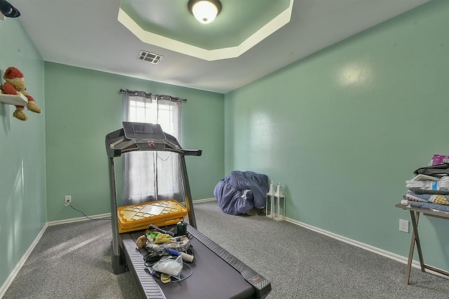 exercise room with carpet and a tray ceiling