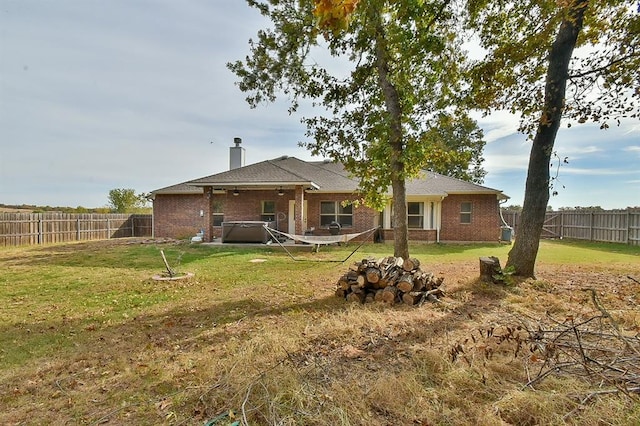 back of property with a yard and a hot tub