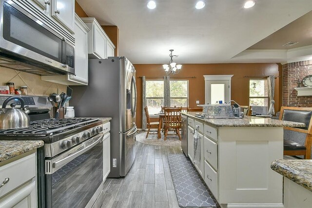 7301 Morning Song Dr, Oklahoma City, OK 73150 - kitchen with stainless steel appliances, a chandelier, white cabinets, light wood-type flooring, and plenty of natural light