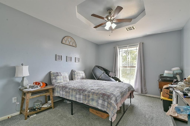 bedroom with carpet flooring, a tray ceiling, and ceiling fan