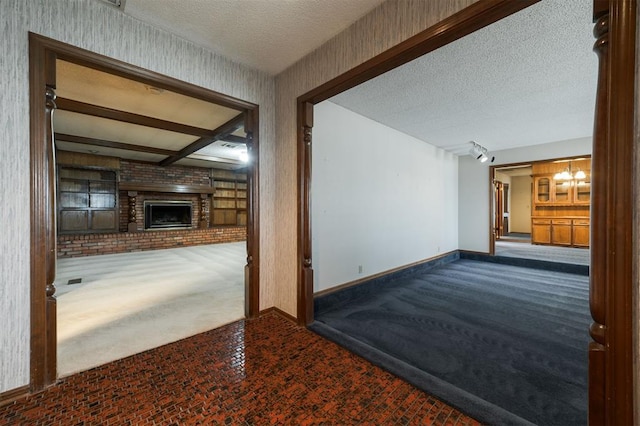 interior space with carpet, a fireplace, a textured ceiling, beam ceiling, and a chandelier