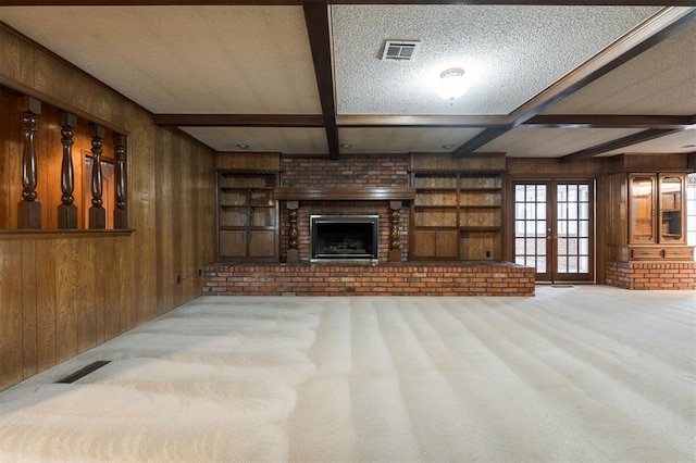 unfurnished living room featuring light carpet, french doors, wooden walls, and beamed ceiling