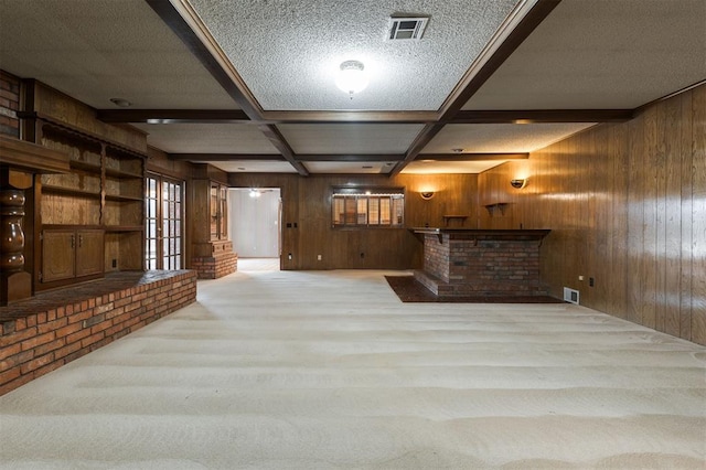 unfurnished living room featuring beam ceiling, wooden walls, light colored carpet, and coffered ceiling