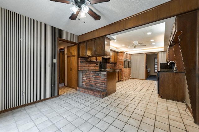 kitchen with ceiling fan, sink, kitchen peninsula, a textured ceiling, and light tile patterned flooring