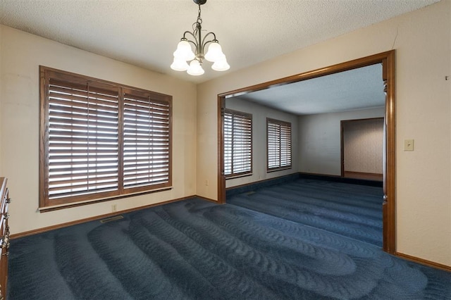 carpeted empty room with a textured ceiling and an inviting chandelier