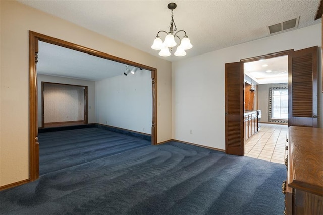 unfurnished room featuring a textured ceiling, carpet floors, and a notable chandelier