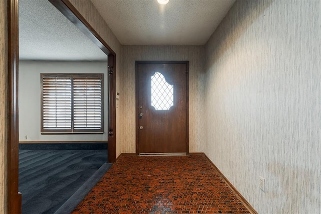 entryway featuring dark carpet and a textured ceiling