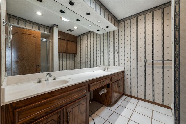 bathroom with tile patterned floors, vanity, a textured ceiling, and walk in shower