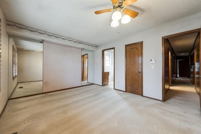 unfurnished bedroom featuring ceiling fan, light colored carpet, and a textured ceiling