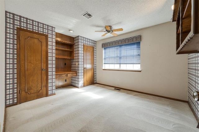 unfurnished bedroom featuring a textured ceiling, ceiling fan, light carpet, and connected bathroom