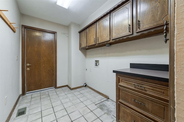 washroom featuring hookup for a washing machine, light tile patterned flooring, and cabinets