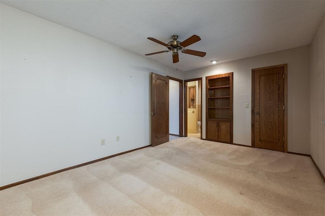 unfurnished bedroom with ceiling fan, light colored carpet, a textured ceiling, and connected bathroom