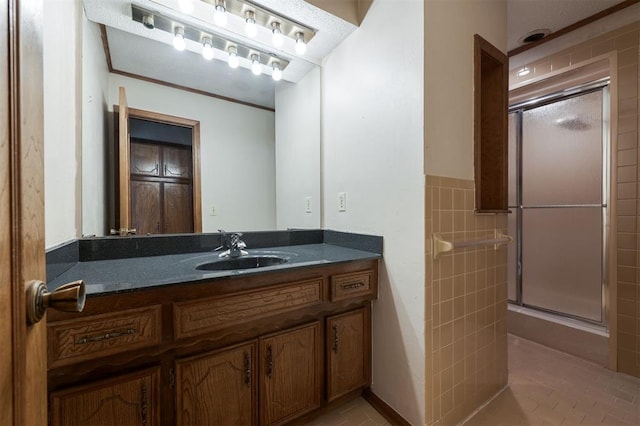 bathroom featuring vanity, a shower with shower door, and tile walls