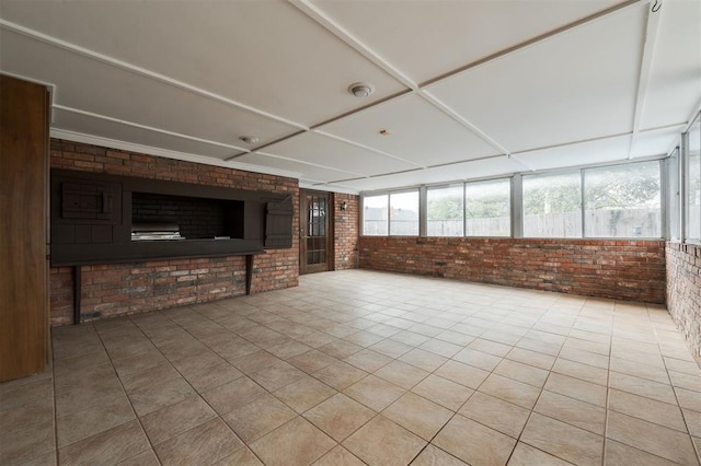 unfurnished living room featuring light tile patterned flooring and brick wall