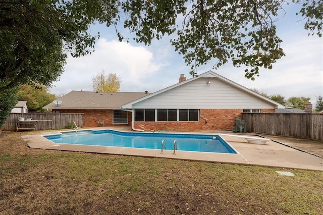 view of pool with a yard, a diving board, and a patio area