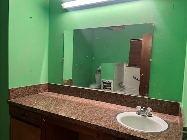 bathroom with a tub to relax in, vanity, and toilet