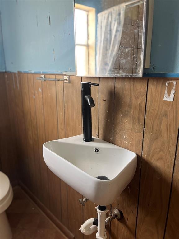 bathroom featuring wood walls, toilet, and sink