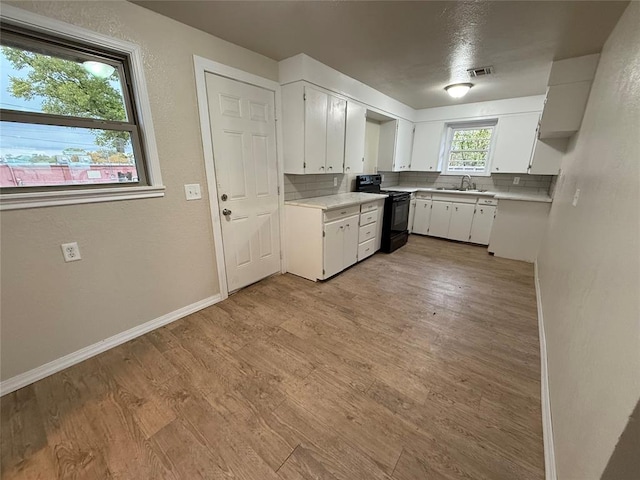 kitchen featuring white cabinets, black electric range oven, plenty of natural light, and sink