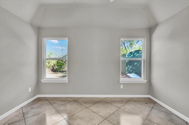 empty room featuring light tile patterned floors and vaulted ceiling