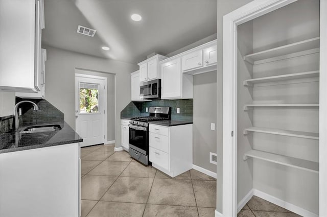 kitchen featuring dark stone counters, white cabinets, sink, decorative backsplash, and appliances with stainless steel finishes