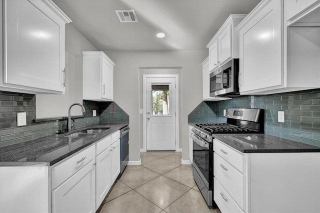 kitchen with white cabinets, light tile patterned floors, backsplash, and stainless steel appliances