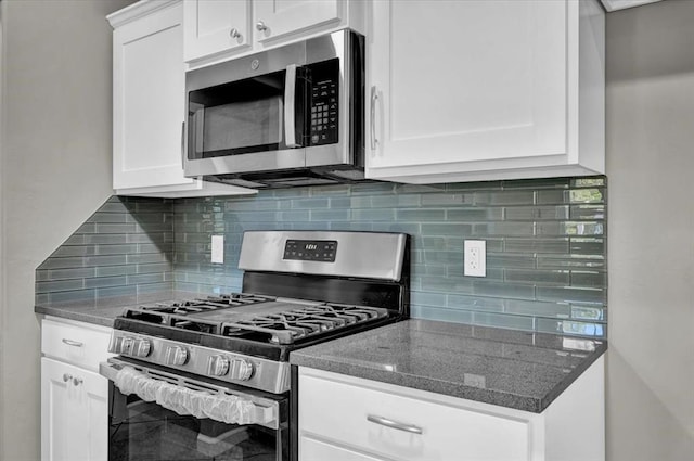 kitchen with tasteful backsplash, dark stone countertops, white cabinetry, and appliances with stainless steel finishes