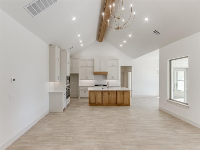 kitchen featuring a center island with sink, white cabinets, sink, light hardwood / wood-style flooring, and vaulted ceiling with beams