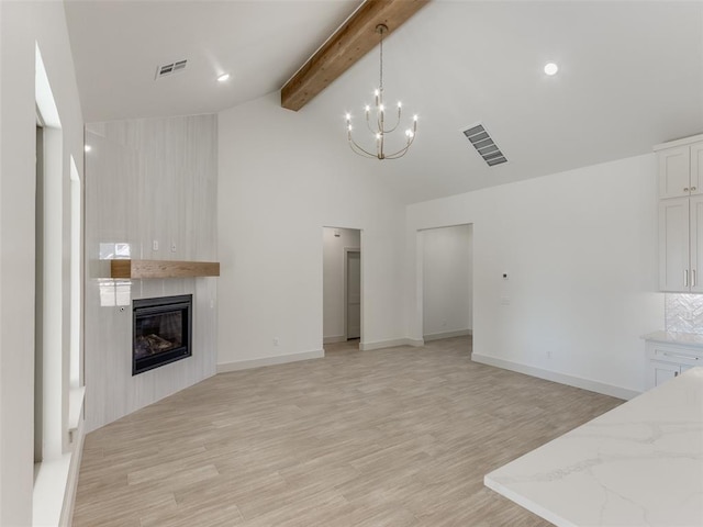 unfurnished living room featuring high vaulted ceiling, light hardwood / wood-style floors, beam ceiling, a large fireplace, and a chandelier