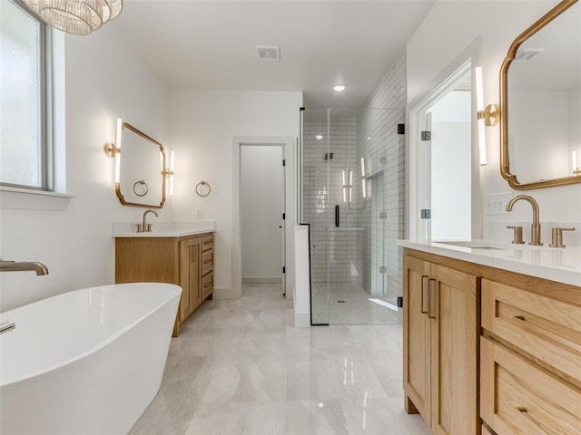 bathroom with a notable chandelier, vanity, and separate shower and tub