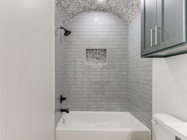 bathroom featuring toilet and tiled shower / bath