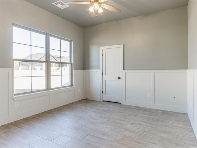 empty room with ceiling fan and light hardwood / wood-style flooring