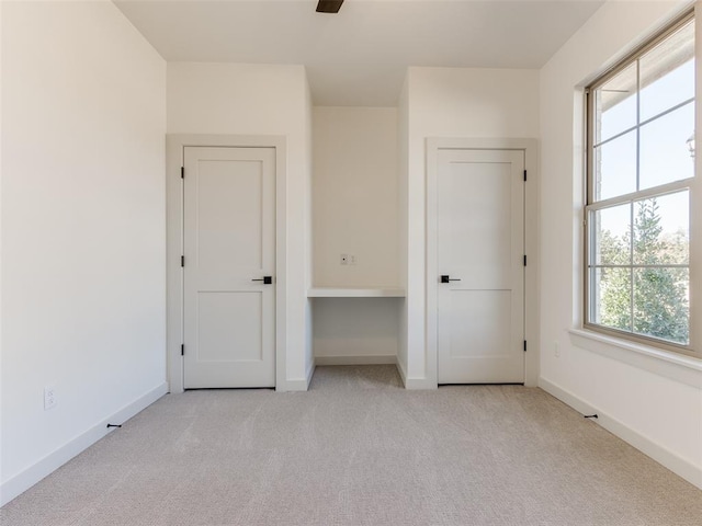 unfurnished bedroom with light colored carpet, multiple windows, and ceiling fan