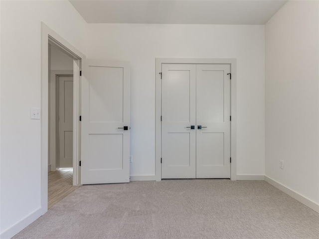 unfurnished bedroom featuring light carpet and a closet