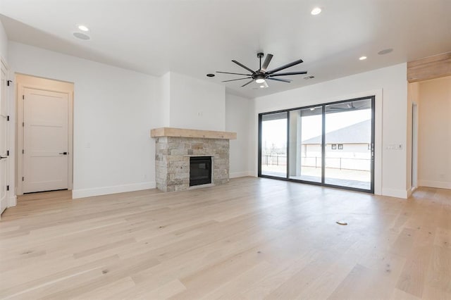 unfurnished living room with light hardwood / wood-style floors, a stone fireplace, and ceiling fan