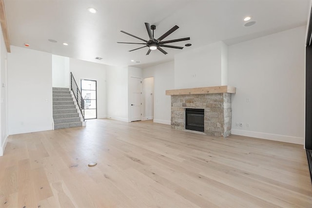 unfurnished living room featuring ceiling fan, a fireplace, and light hardwood / wood-style flooring